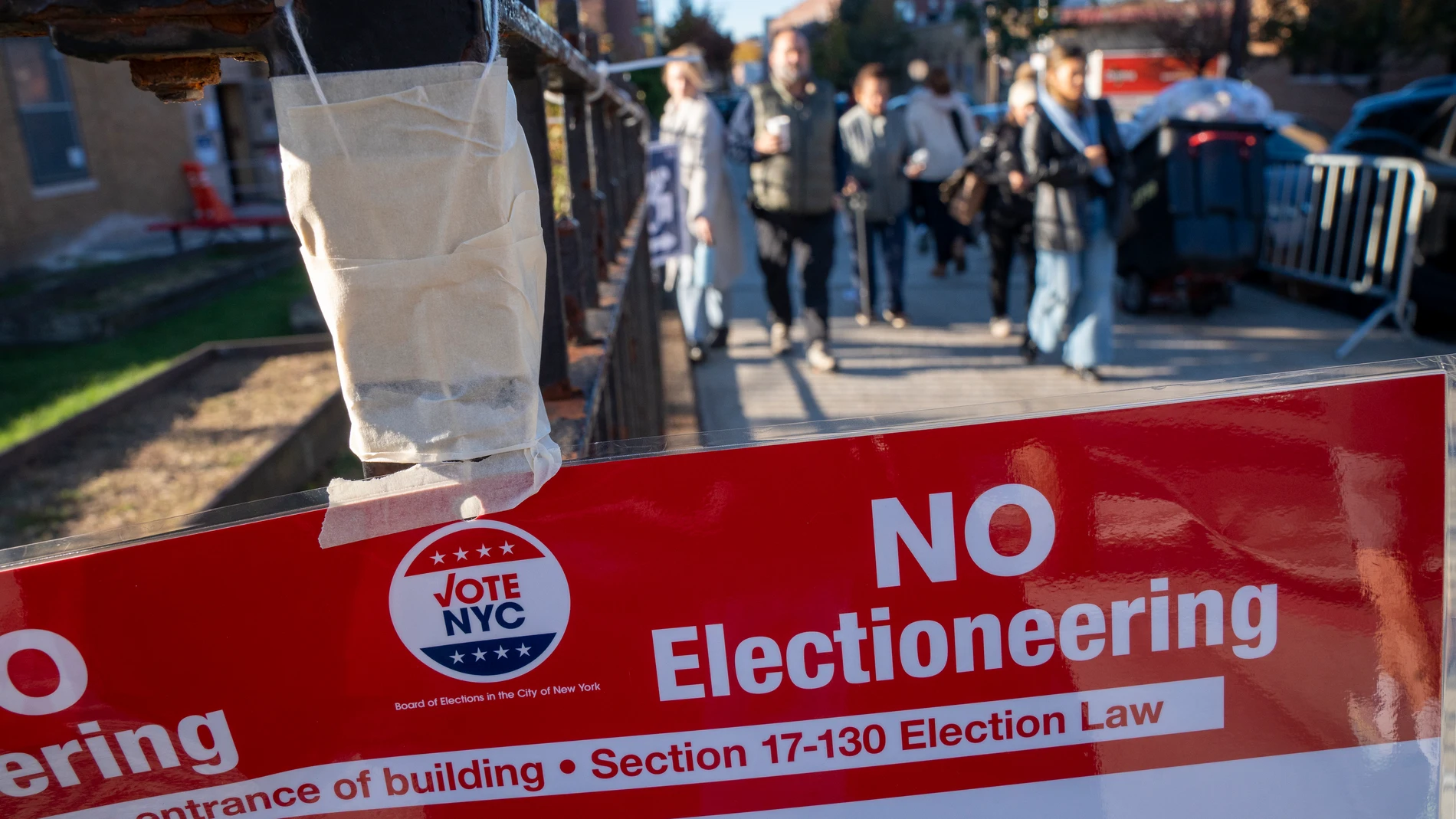 AME5429. QUEENS (ESTADOS UNIDOS), 04/11/2025.- Personas caminan frente a un cartel cerca a un centro de votación este martes, en Queens (Estados Unidos). Millones de estadounidenses están llamados a las urnas para elegir alcalde en ciudades como Nueva York y Miami, gobernador en estados como Nueva Jersey y Virginia, o para decidir sobre un nuevo mapa electoral para las elecciones al Congreso en California, justo cuando se cumple prácticamente un año de la victoria del presidente, Donald Trump...