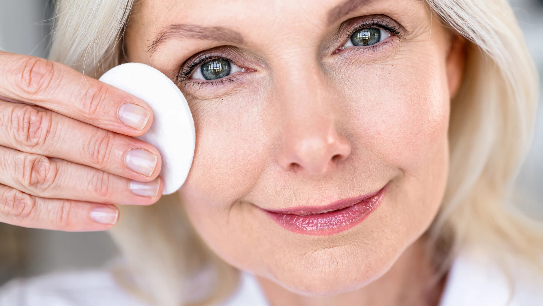 Mujer madura desmaquillándose el contorno de ojos con un disco de algodón.