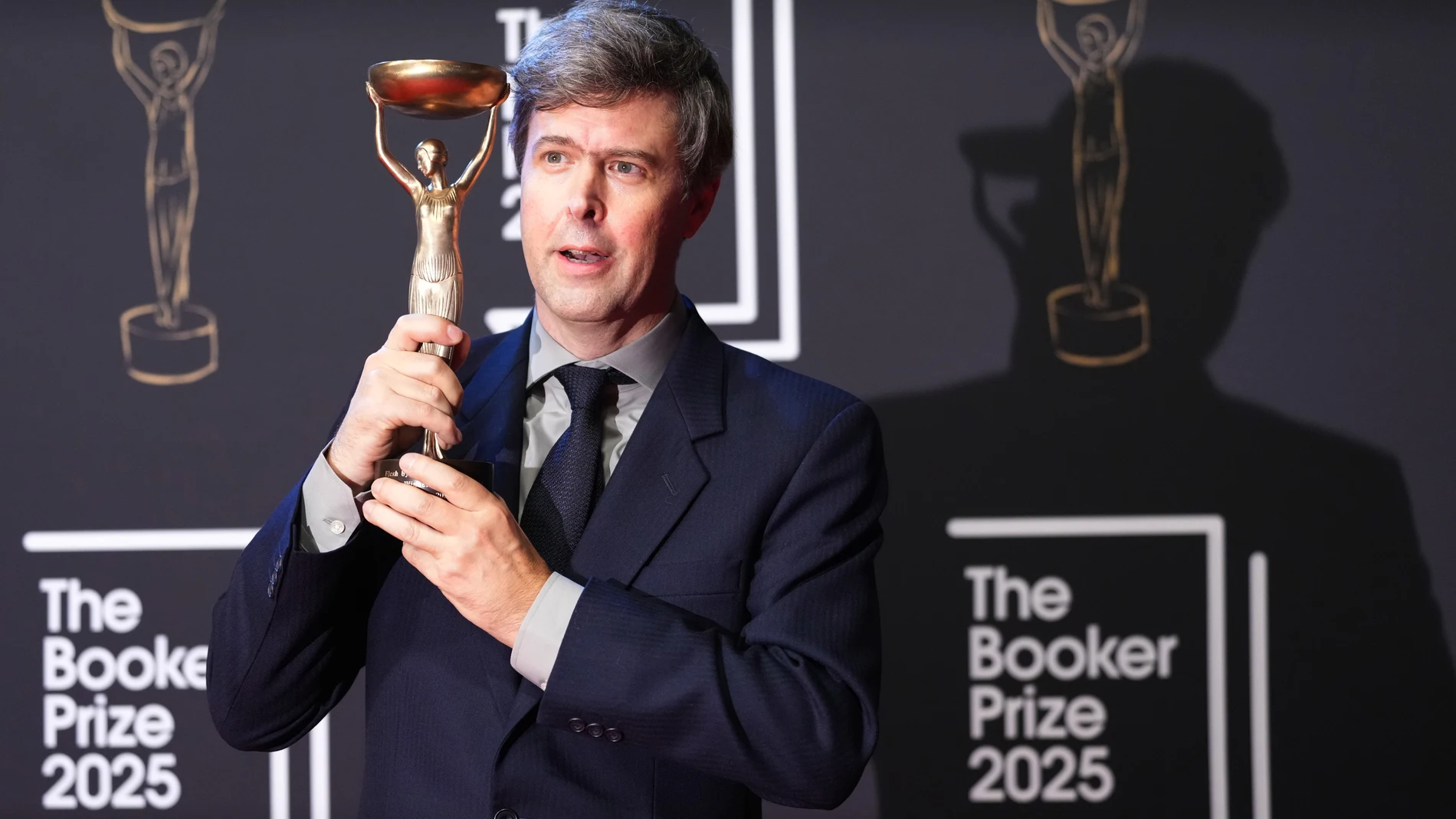 Hungarian-British author David Szalay poses for photographers with the trophy after winning the Booker Prize 2025 for his book 'Flesh' during a ceremony at Old Billingsgate in London, Monday, Nov. 10, 2025. (AP Photo/Kirsty Wigglesworth)