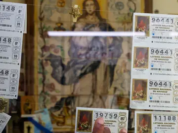 Lotería de Navidad GRAFCVA336. VALENCIA, 12/11/2025.- Una persona escoge un décimo en una administración de lotería durante la mañana de este miércoles en la que se ha presentado la tradicional campaña publicitaria del Sorteo Extraordinario de Lotería de 2025, para el que se han puesto a la venta 198 millones de décimos que repartirán 2.772 millones de euros en premios. EFE/Ana Escobar