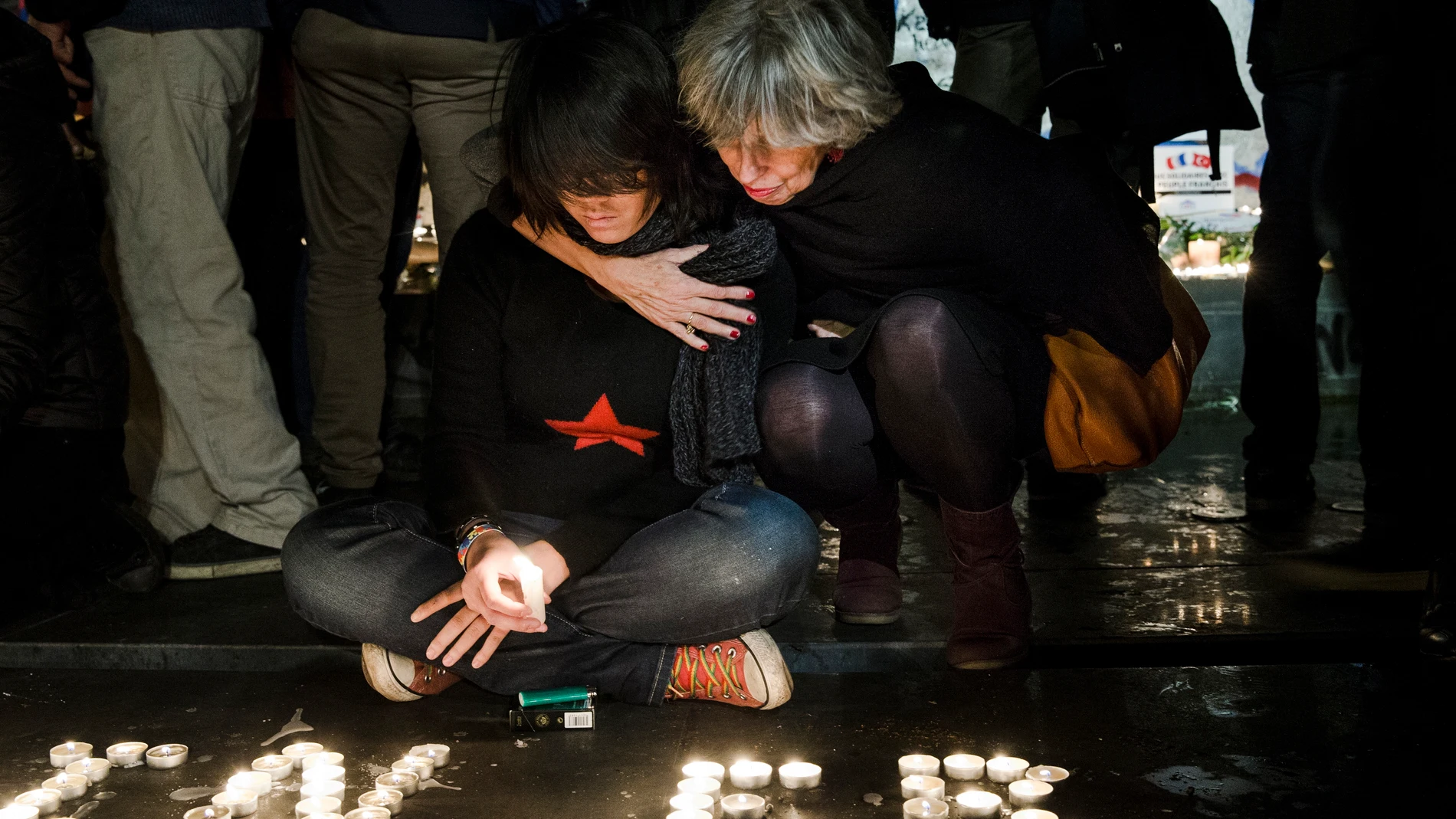 Personas encienden velas en la Plaza de la República en París, en homenaje a las víctimas de los atentados del 13-N en París
