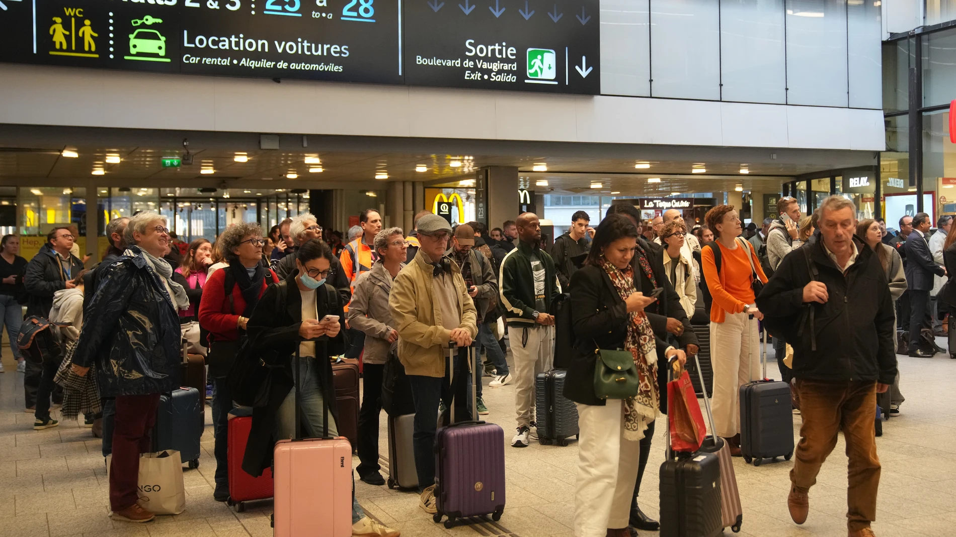 Travelers wait for their train at the Montparnasse train station after a man wielding a knife at the station was shot and wounded by police, Friday, Nov. 14, 2025 in Paris. (AP Photo/Christophe Ena)