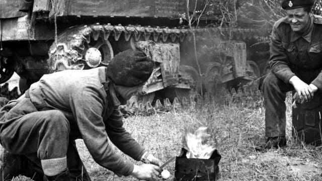 Unos soldados preparan comida y bebida junto a un tanque Unos soldados preparan comida y bebida junto a un tanque