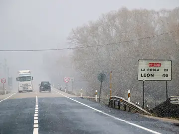 Varios vehículos circulan por una carretera nevada de León Varios vehículos circulan por una carretera nevada de León
