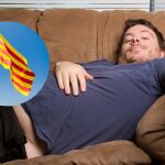 Una persona tirada en el sofá junto con la bandera de Cataluña