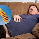 Una persona tirada en el sofá junto con la bandera de Cataluña