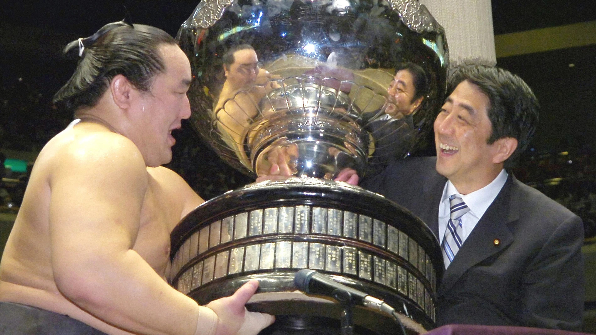 FILE - Grand champion Asashoryu of Mongolia, left, receives the Prime Minister's Cup from Chief Cabinet Secretary and soon-to-be Premier Shinzo Abe at Tokyo's Ryogoku Sumo Arena on Sept. 24, 2006. (Kyodo News via AP, File)