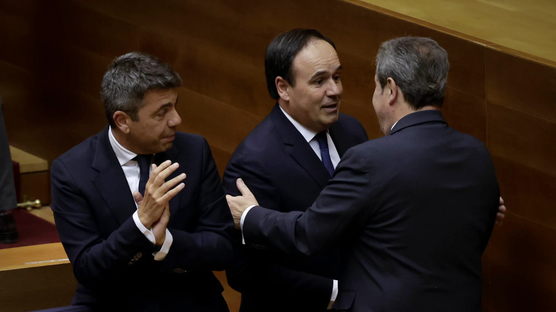 El síndico de Vox, José María Llanos, saluda al presidente in pectore, Pérez Llorca, en presencia del presidente saliente, Carlos Mazón