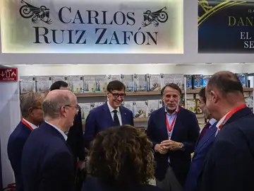 Salvador Illa, presidente de la Generalitat, junto a José Creuheras, presidente del Grupo Planeta y Atresmedia, frente al stand dedicado a Carlos Ruiz Zafón Salvador Illa, presidente de la Generalitat, junto a José Creuheras, presidente del Grupo Planeta y Atresmedia, frente al stand dedicado a Carlos Ruiz Zafón