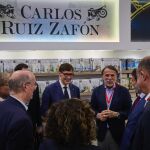 Salvador Illa, presidente de la Generalitat, junto a Jos&eacute; Creuheras, presidente del Grupo Planeta y Atresmedia, frente al stand dedicado a Carlos Ruiz Zaf&oacute;n