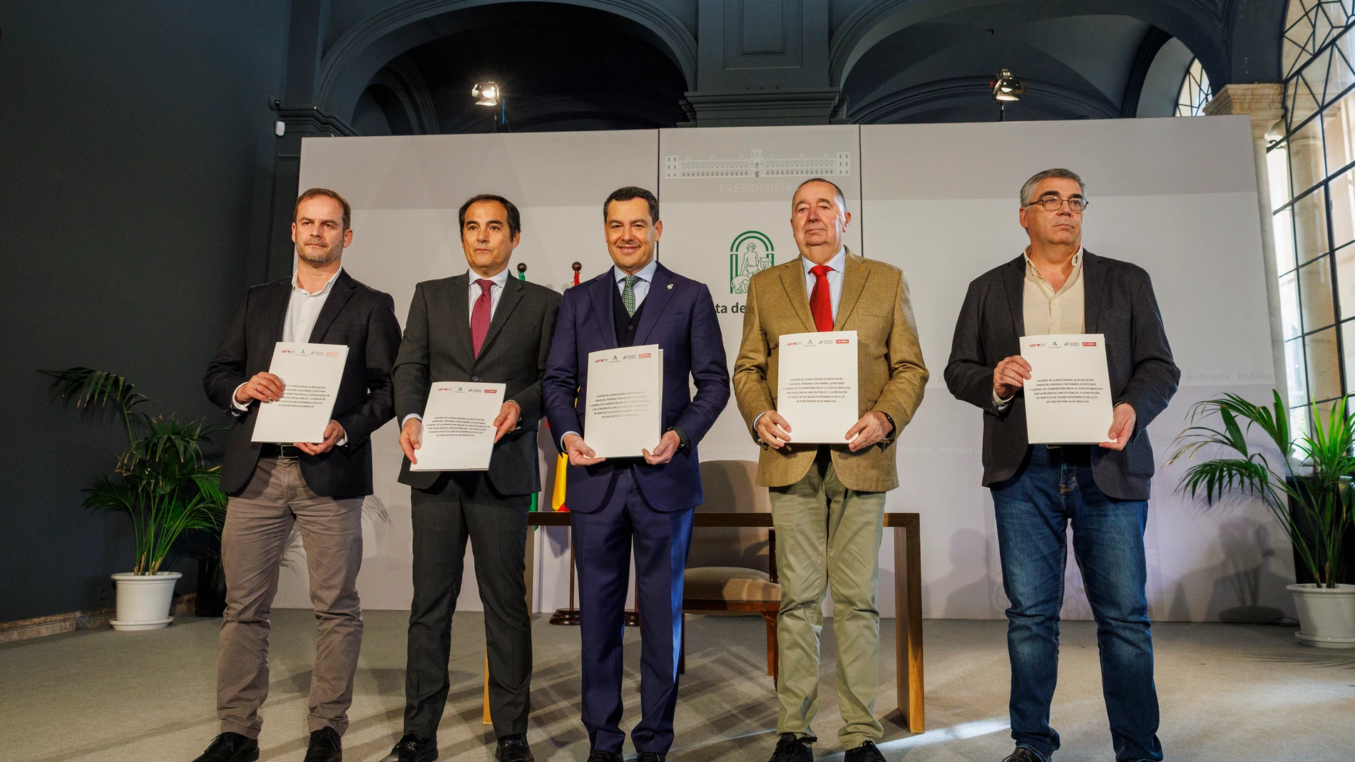 GRAFAND2557. SEVILLA, 09/12/2025.- El presidente de la Junta de Andalucía, Juanma Moreno(c), junto al consejero de Justicia, Administración Local y Función, José Antonio Nieto (2i), y los representantes de los sindicatos CSIF, Manuel Moreno (i); de UGT, Antonio Tirado (2d), y de CCOO, José Pelayo Galindo (d), tras la firma del acuerdo por la mejora del empleo público, la prestación de servicios de calidad y el desarrollo de la Ley de Función Pública, este martes en el Palacio de San Telmo en ...