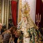 Una mujer besa la mano de la imagen de la Esperanza Macarena 