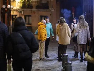 Varios jóvenes fuman a la salida de un bar Varios jóvenes fuman a la salida de un bar