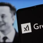  Logo del chatbot Grok integrado en X sobre el perfil de fondo del due&ntilde;o de la plataforma, Elon Musk.