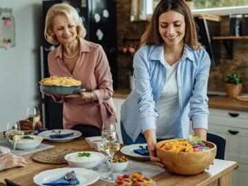 Mujeres colocan en la mesa alimentos t&iacute;picos de la dieta mediterr&aacute;nea