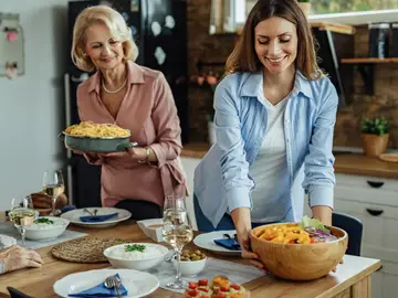 Mujeres colocan en la mesa alimentos típicos de la dieta mediterránea Mujeres colocan en la mesa alimentos típicos de la dieta mediterránea