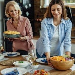 Mujeres colocan en la mesa alimentos t&iacute;picos de la dieta mediterr&aacute;nea