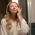 mujer en el bano retirando el maquillaje del rostro con una toallita desmaquillante