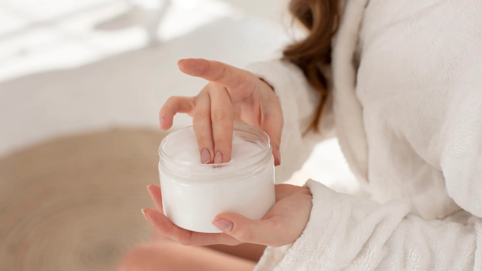mujer en bata aplicando crema como parte de su rutina