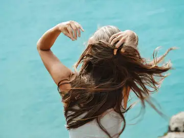mujer de espaldas con el pelo suelto al viento junto al mar en verano mujer de espaldas con el pelo suelto al viento junto al mar en verano