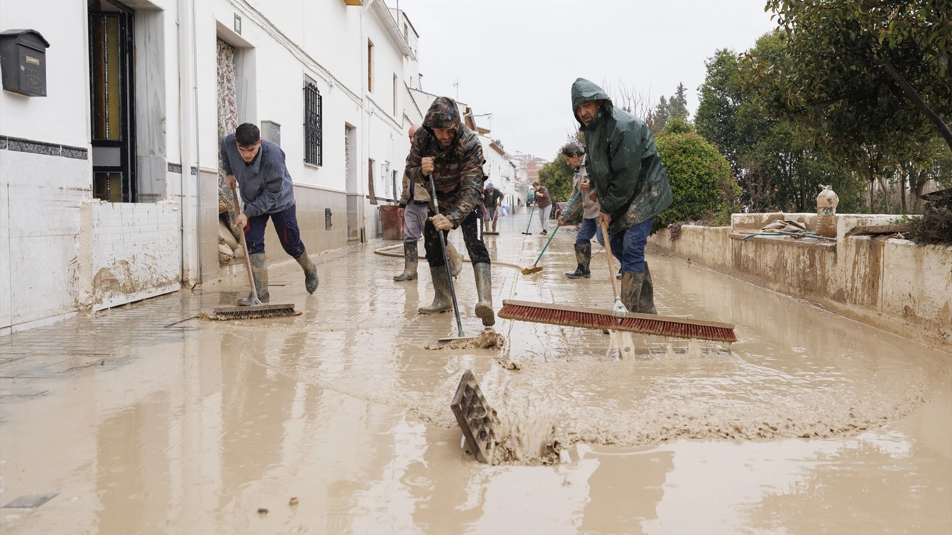 Vecinos de Villanueva Mesía (Granada) se afanan en sacar el agua y barro de sus casas tras la crecida del Río Genil por el paso de la borrasca 'Leonardo'