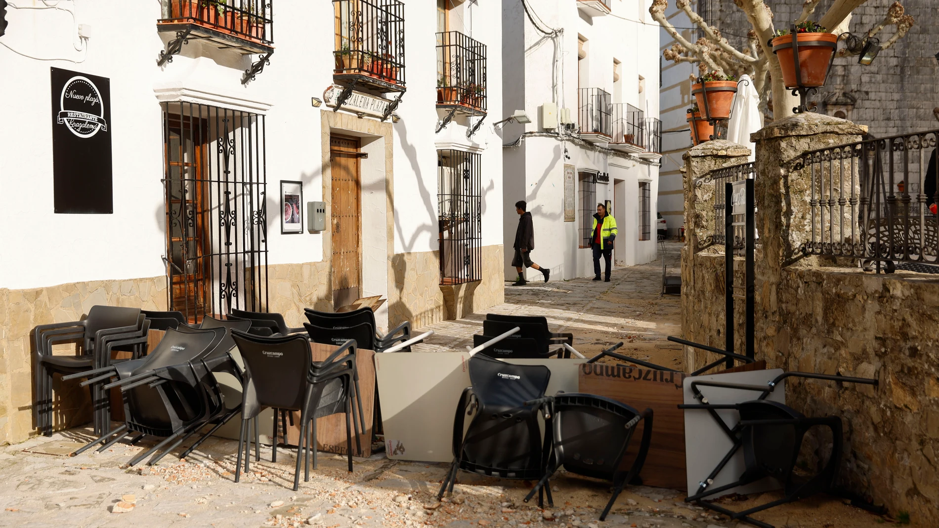 GRAZALEMA (CÁDIZ), 16/02/2026.- Sillas y mesas apiladas en una calle de Grazalema este lunes. Un primer grupo de vecinos desalojados hace 11 días por el temporal en Grazalema (Cádiz) ha podido volver a sus hogares a partir de las 16:05 horas de este lunes, cuando la Guardia Civil ha permitido el acceso a una treintena de vehículos al municipio. EFE/ Jorge Zapata