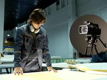 Imagen de archivo de un trabajador junto a una cámara de vídeo Imagen de archivo de un trabajador junto a una cámara de vídeo