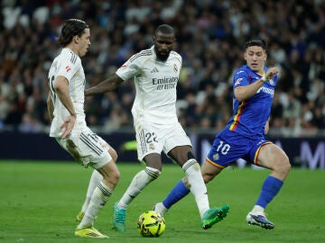 MADRID, 02/03/2026.- Los jugadores del Real Madrid, &Aacute;lvaro Carreras (i) y el alem&aacute;n Antonio R&uuml;diger, disputan el bal&oacute;n ante el delantero uruguayo del Getafe, Mart&iacute;n Satriano, durante el encuentro correspondiente a la jornada 26 de Laliga EA Sports que disputan este lunes en el estadio Santiago Bernab&eacute;u, en Madrid. EFE / Juanjo Mart&iacute;n. 