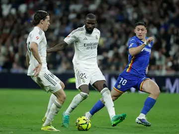 REAL MADRID / GETAFE MADRID, 02/03/2026.- Los jugadores del Real Madrid, Álvaro Carreras (i) y el alemán Antonio Rüdiger, disputan el balón ante el delantero uruguayo del Getafe, Martín Satriano, durante el encuentro correspondiente a la jornada 26 de Laliga EA Sports que disputan este lunes en el estadio Santiago Bernabéu, en Madrid. EFE / Juanjo Martín.
