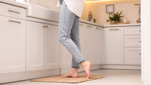 Persona descalza sobre una alfombra en la cocina de su casa