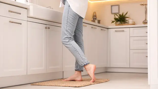 Persona descalza sobre una alfombra en la cocina de su casa Persona descalza sobre una alfombra en la cocina de su casa