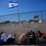 Asistentes a un funeral se ponen a cubierto mientras suenan las sirenas antia&eacute;reas que advierten de la llegada de misiles lanzados por Ir&aacute;n hacia Israel