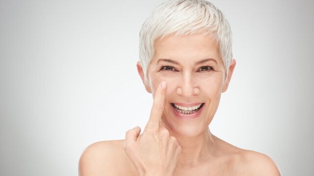 Mujer se&ntilde;alando el contorno de ojos, con ligera ojera y piel luminosa