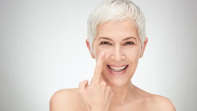 Mujer señalando el contorno de ojos, con ligera ojera y piel luminosa Mujer señalando el contorno de ojos, con ligera ojera y piel luminosa