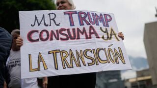 A woman holds a sign with a message that reads in Spanish: "Trump, complete the transition now" at a protest calling for presidential elections and fair wages, at the Alfredo Sadel square in Caracas, Venezuela, Thursday, April 16, 2026. (AP Photo/Ariana Cubillos)