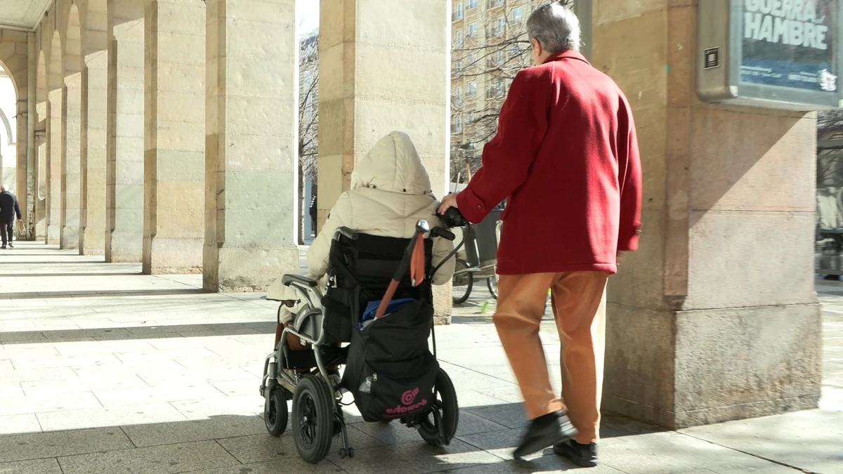 Una persona empuja a otra en silla de ruedas