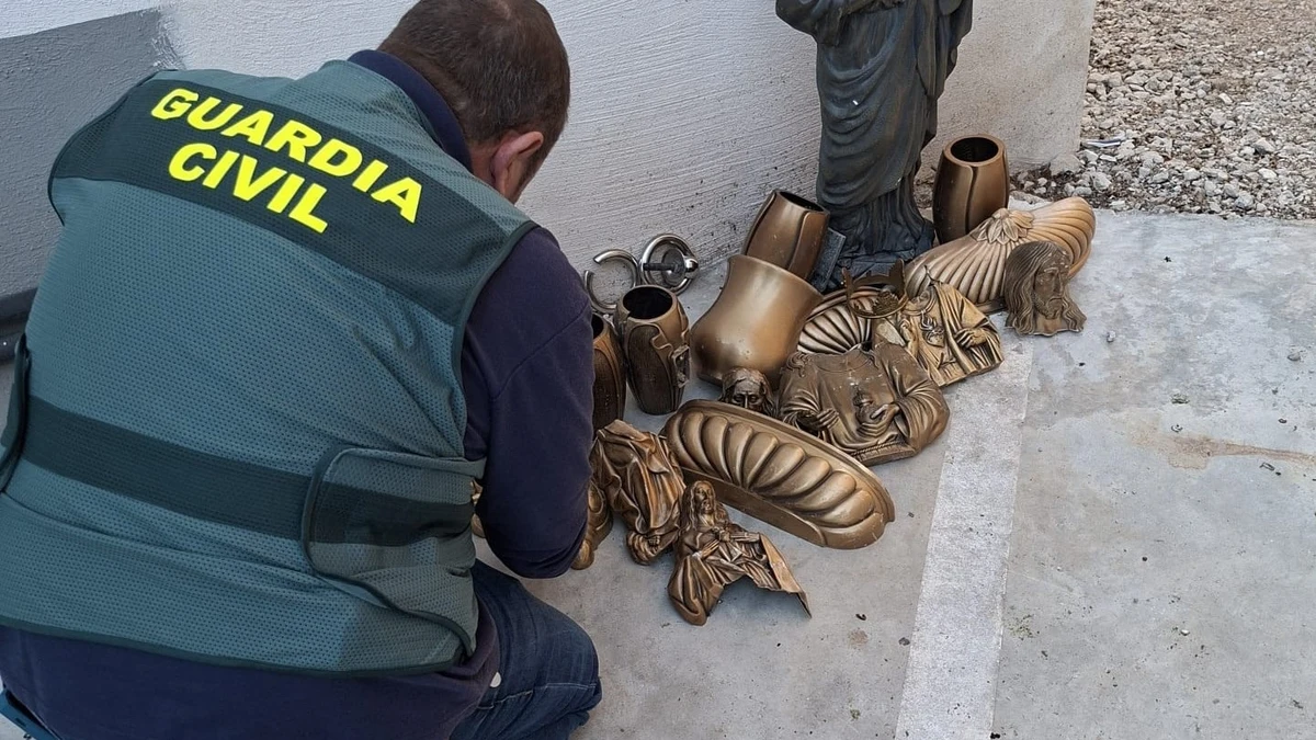 Agente de la Guardia Civil junto a las piezas robadas en el cementerio de Pulianas.